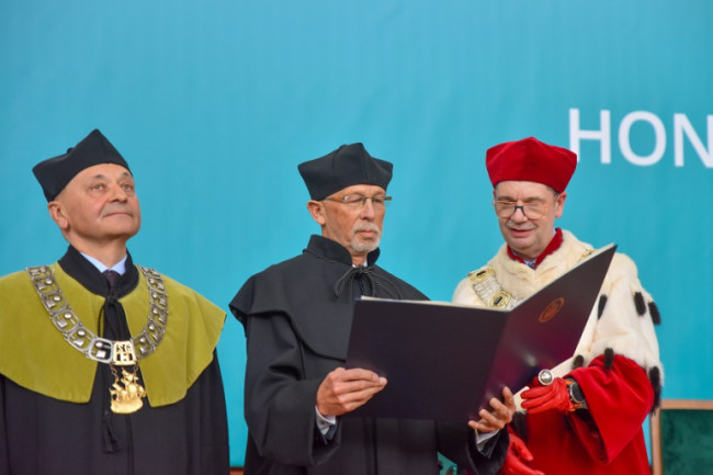 dr Wiesław Rozłucki i rektor Piotr Wachowiak patrzą na otwarty dyplom, obok stoi dziekan Gabriel Główka
